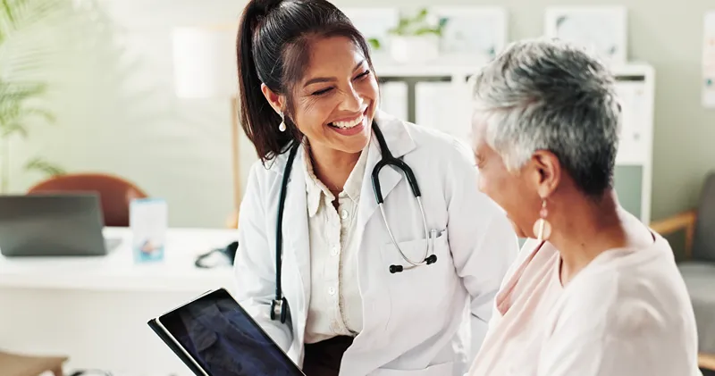 A photo of a doctor showing something on a tablet to their patient