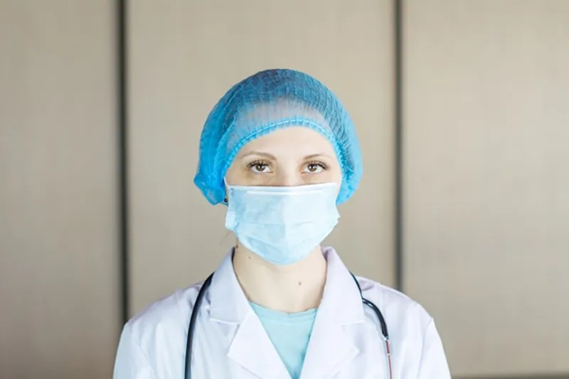A female healthcare professional in blue scrubs stands in a bright, modern clinical setting