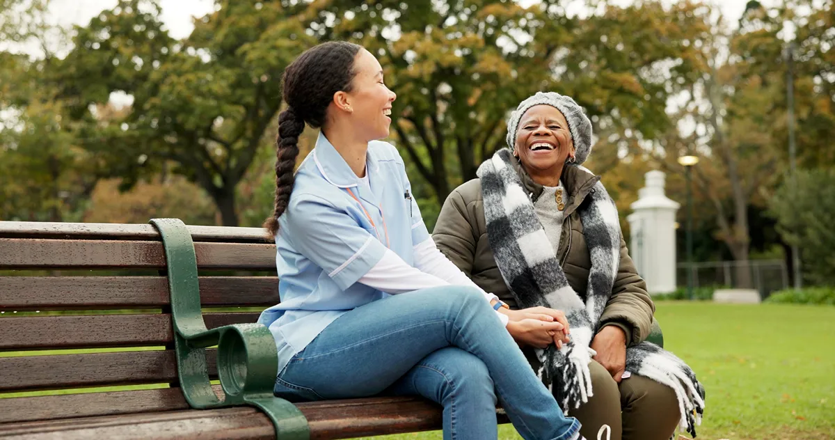 A pair of women sitting on a park bench laughing together