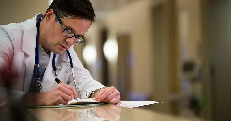 A photo of a doctor writing something on a piece of paper