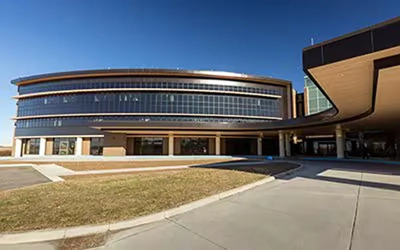 Modern curved building with a glass facade and a prominent covered entrance