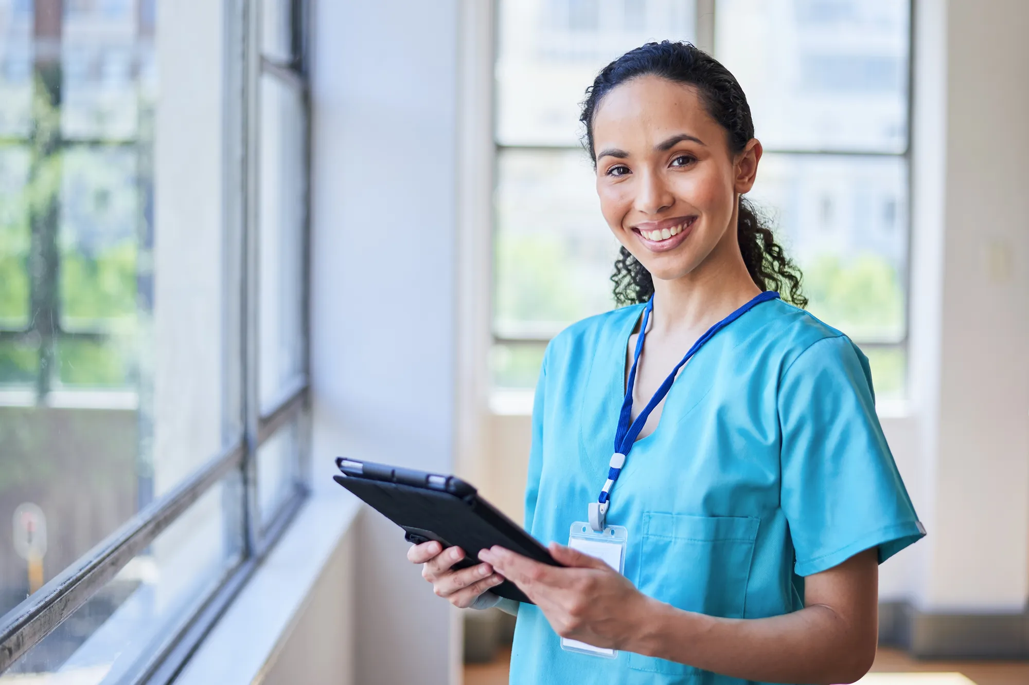 A nurse holding a smart table looks forwards smiling