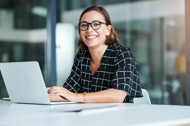 A photo of a woman typing on a keyboard looking at the camera