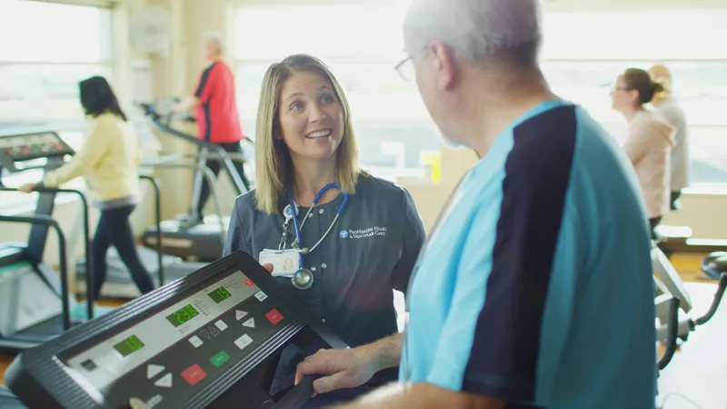 A photo a woman talking to a man walking on a treadmill