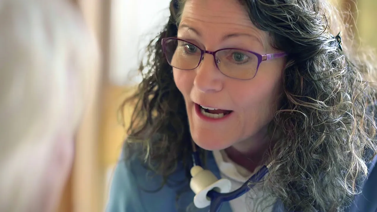 Registered nurse standing in hospital lobby wearing ID badge and white shirt