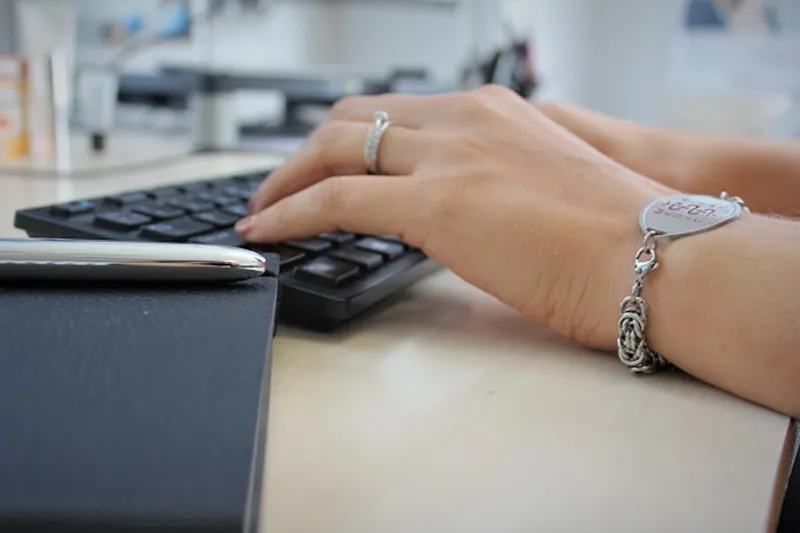 A closeup photo of a pair of hands typing on a keyboard