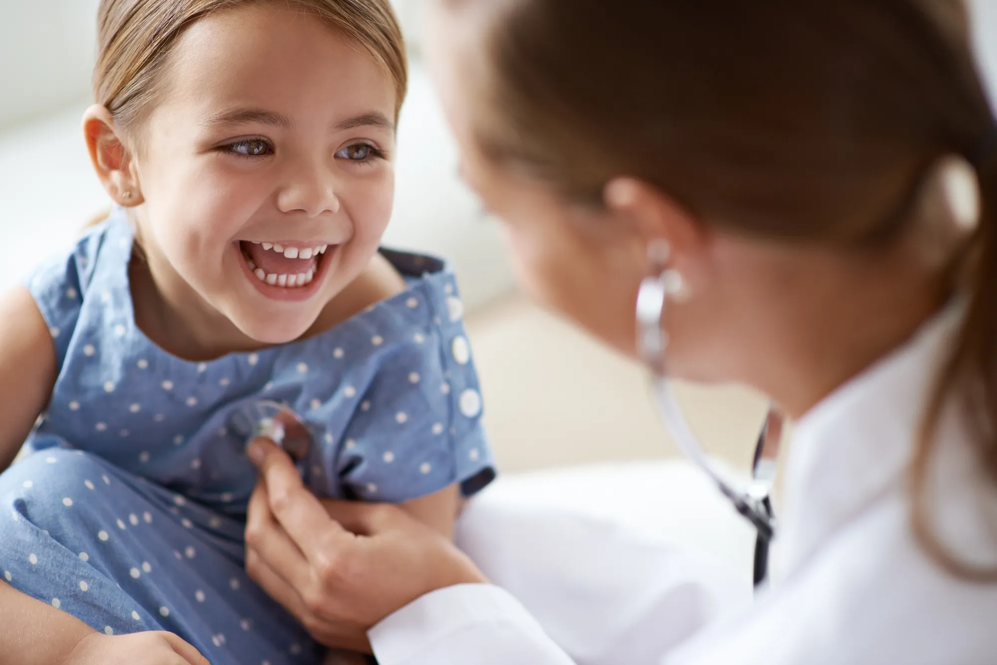 A small child smiling up at the doctor examining them