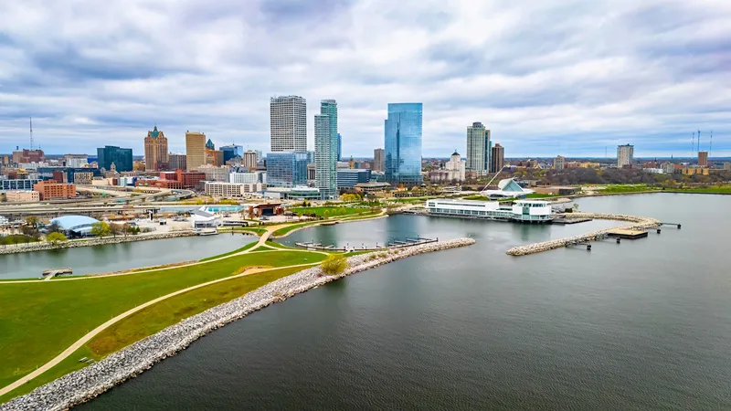 Aerial view of Milwaukee's waterfront skyline with skyscrapers, the Art Museum, and a park along Lake Michigan.