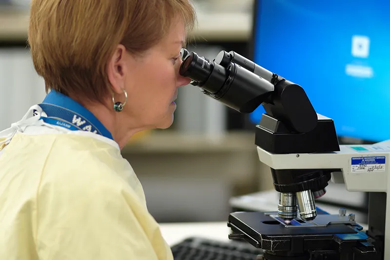 A photo of a female medical professional looking into a magniscope