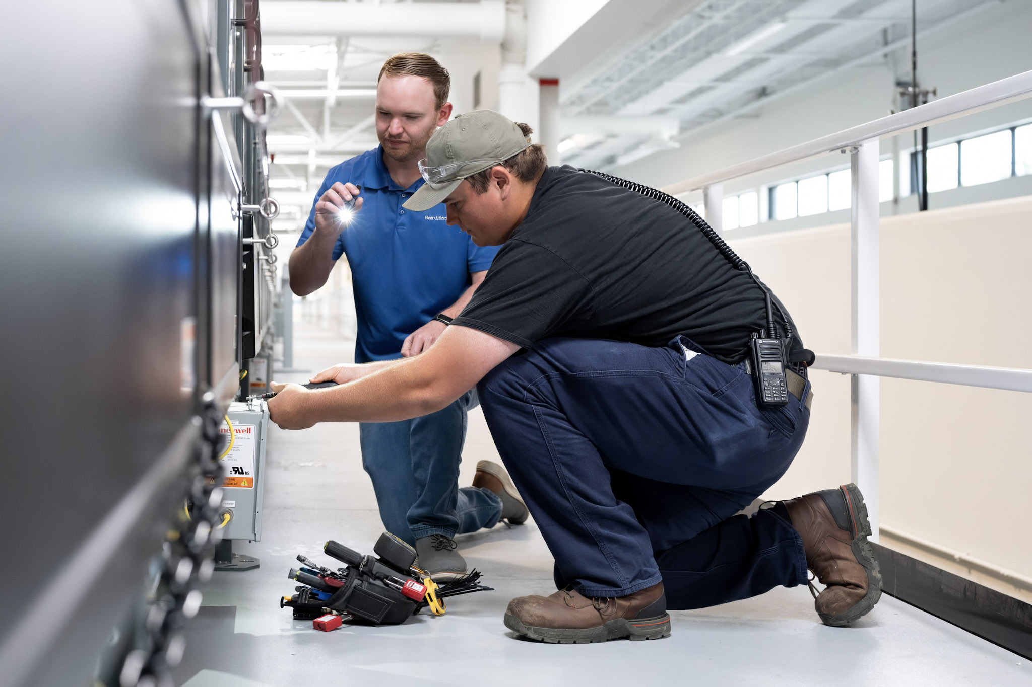 A photo of two men working on an electrical box