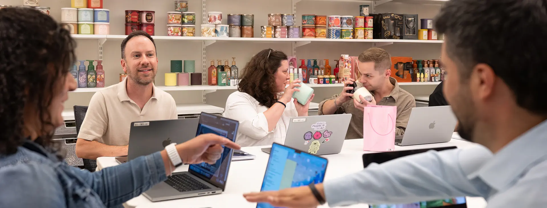 Bath & Body Works associates sitting around a table working on their laptops and smelling candles
