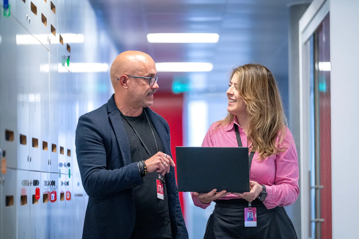 Two colleagues discussing business strategy with laptop in modern office environment