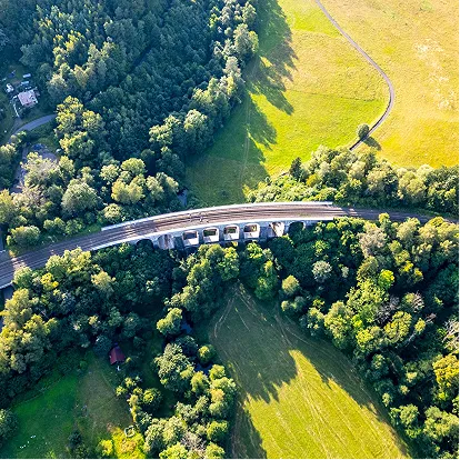 Aerial view of highway bridge through lush green forest representing sustainability