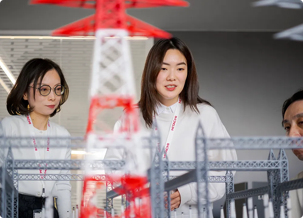 Engineer in research facility with red structural model representing Hitachi's ethical commitment