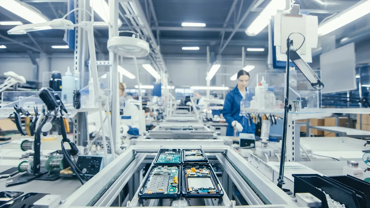 Manufacturing facility with industrial robotics and worker operating advanced equipment