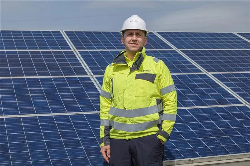 Hitachi engineer in safety gear standing at solar panel installation