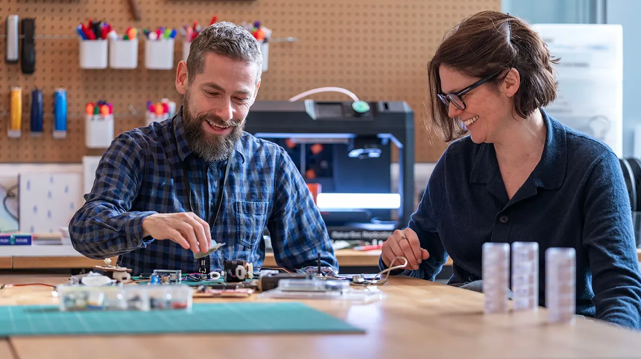 Two Hitachi engineers collaborating on electronic components in a workshop