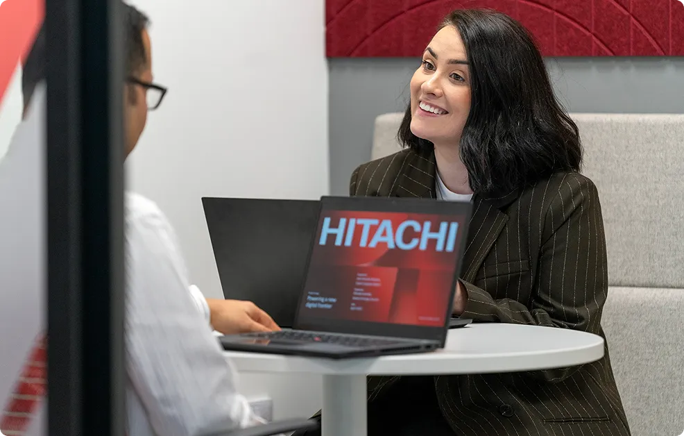 Hitachi employees having a friendly conversation with laptop showing company presentation