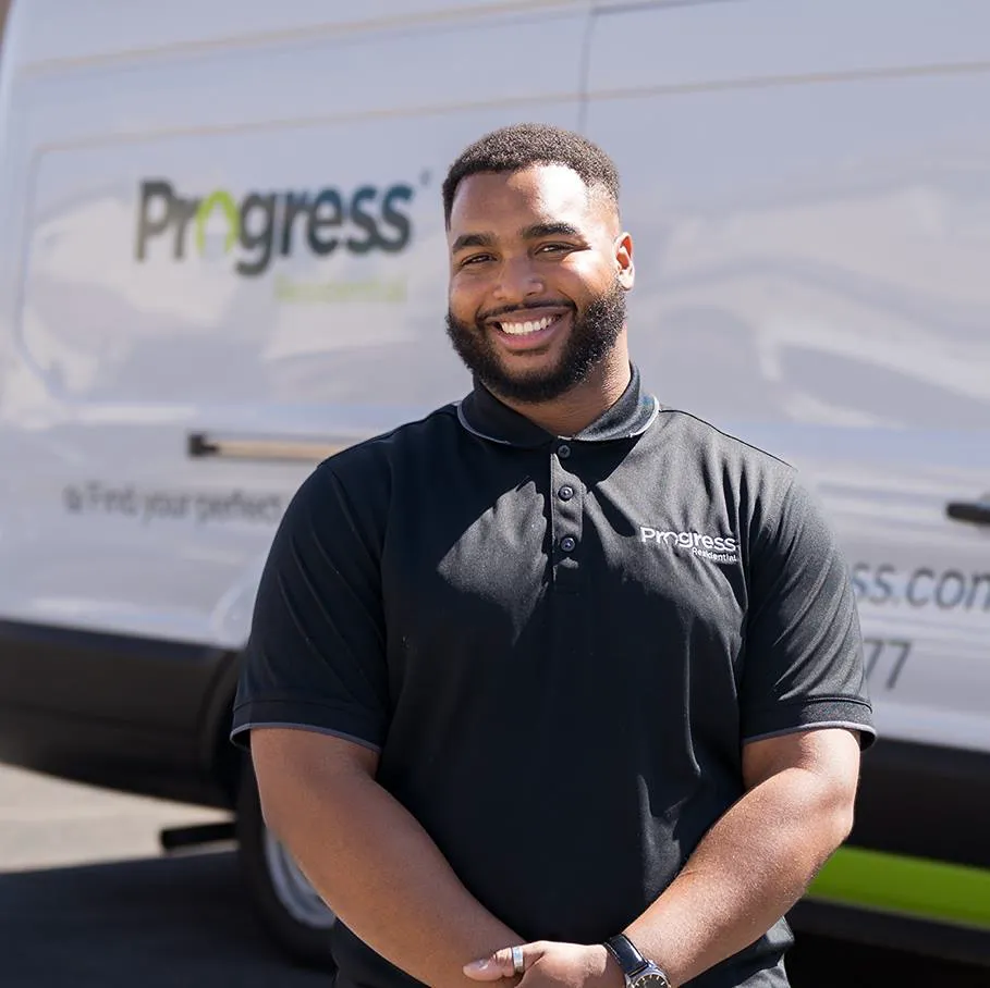 Smiling Progress Residential employee standing by a company van.